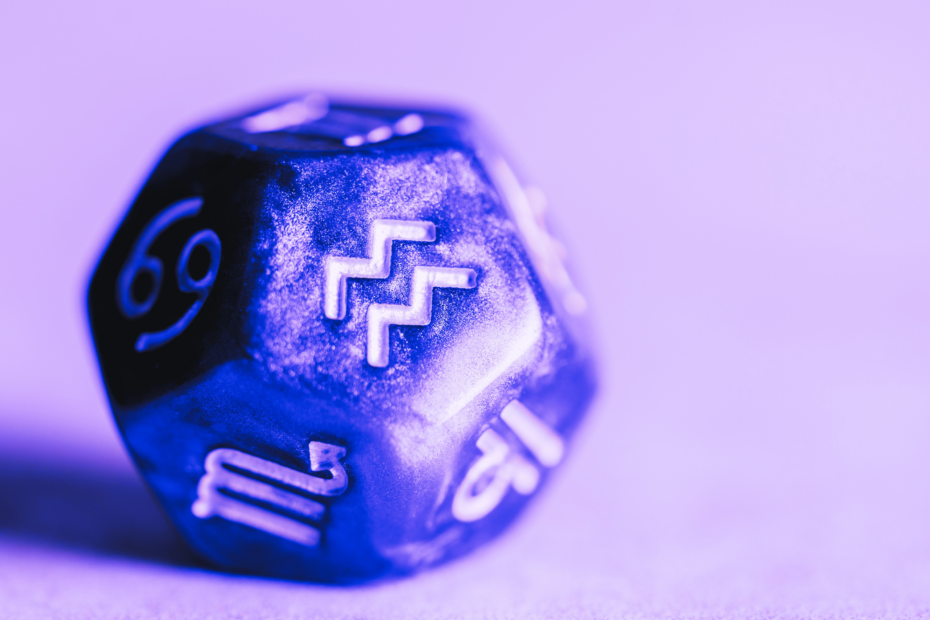 A dice with signs of the zodiac on it showing the symbol for Aquarius